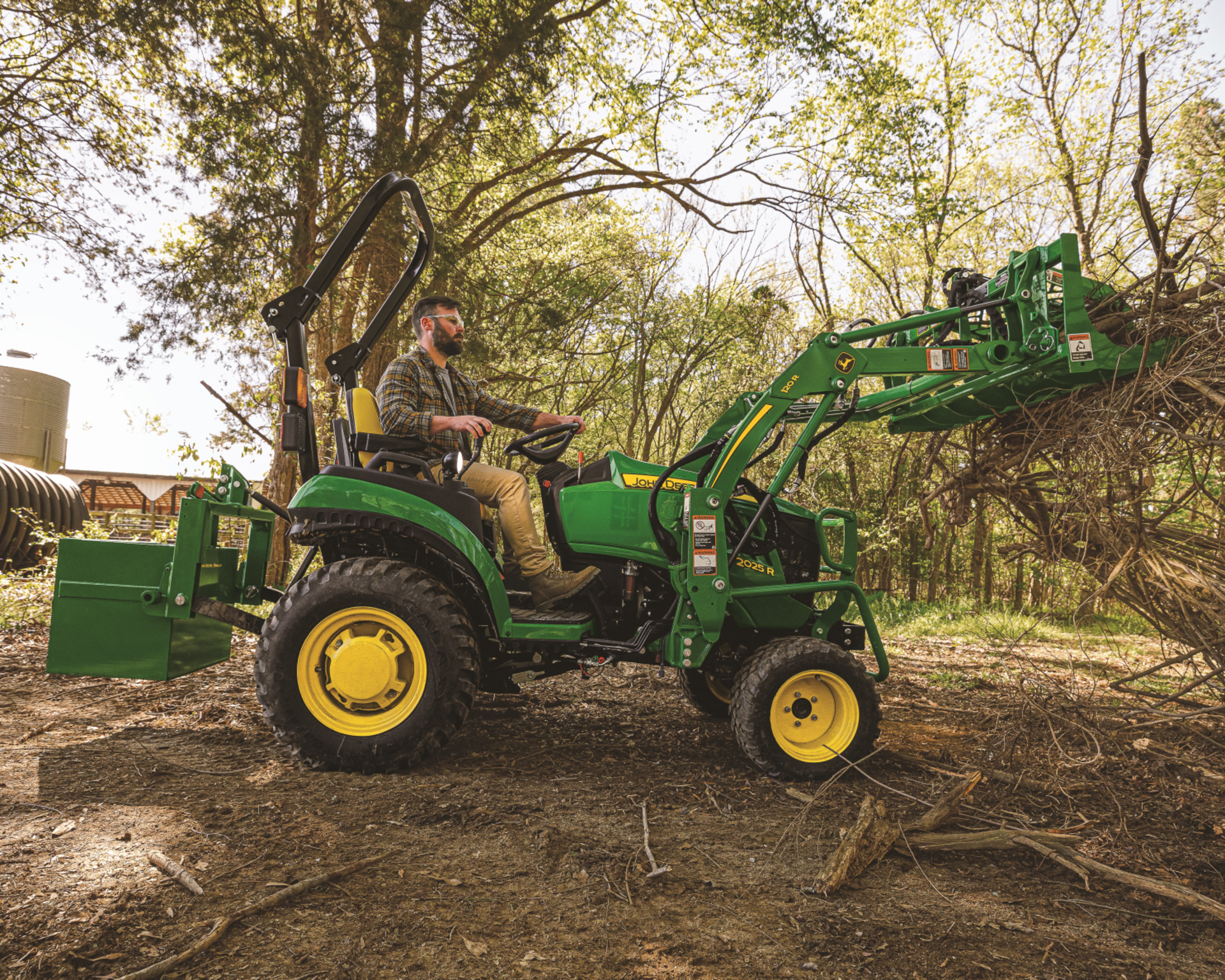 A man operates a John Deere compact tractor on a Texas ranch.