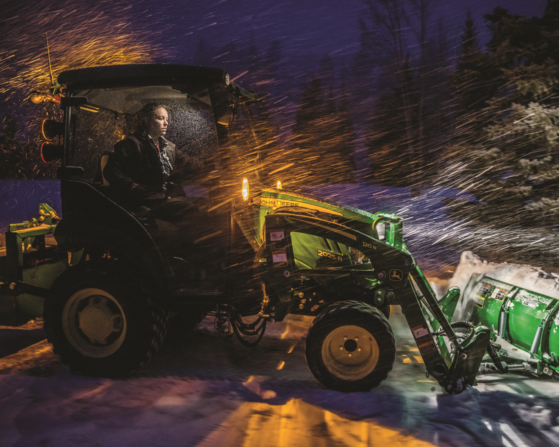 A man pushes snow with a snow plow attachment on a ranch.