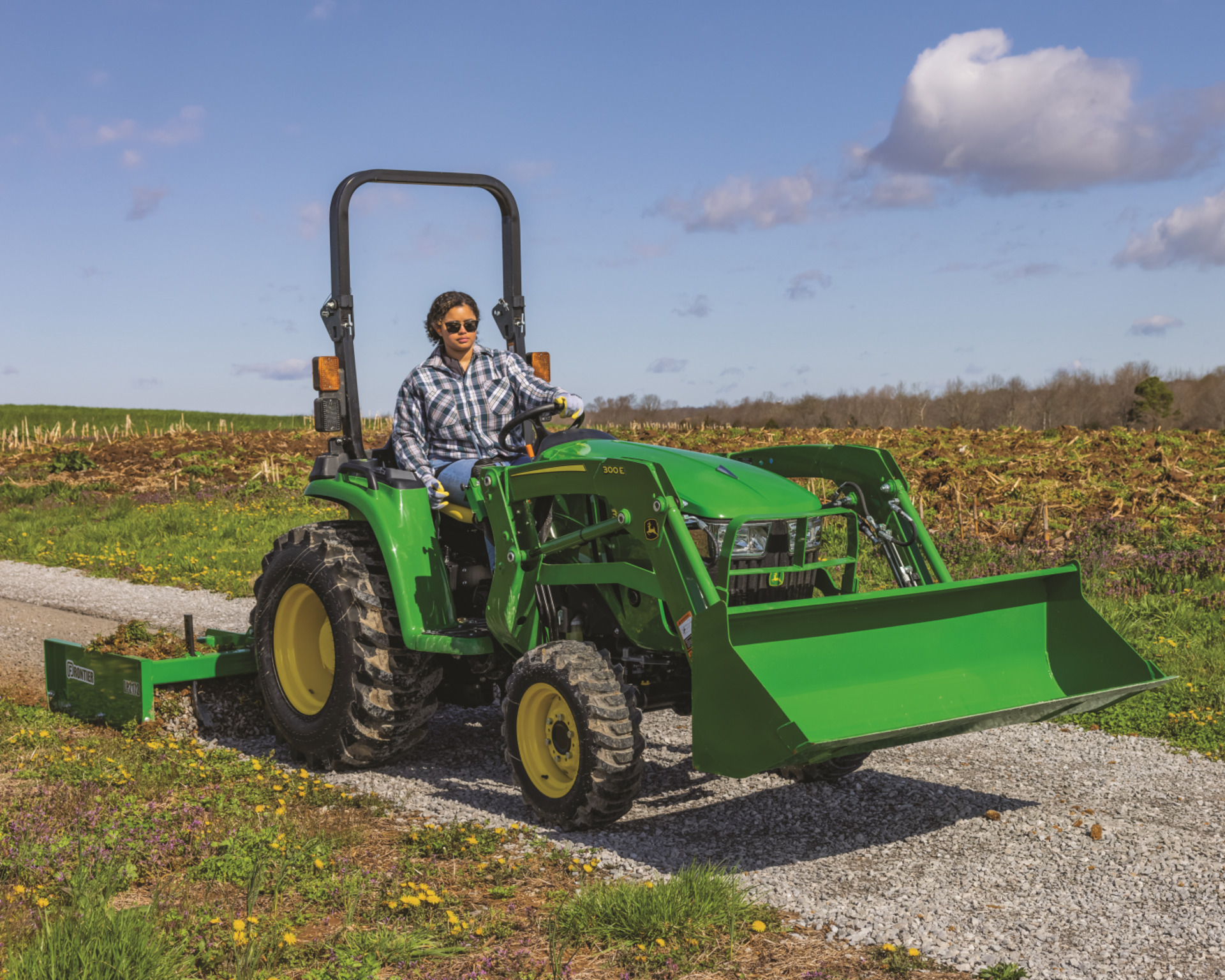 A property owner uses their John Deere 3038E to level a road.