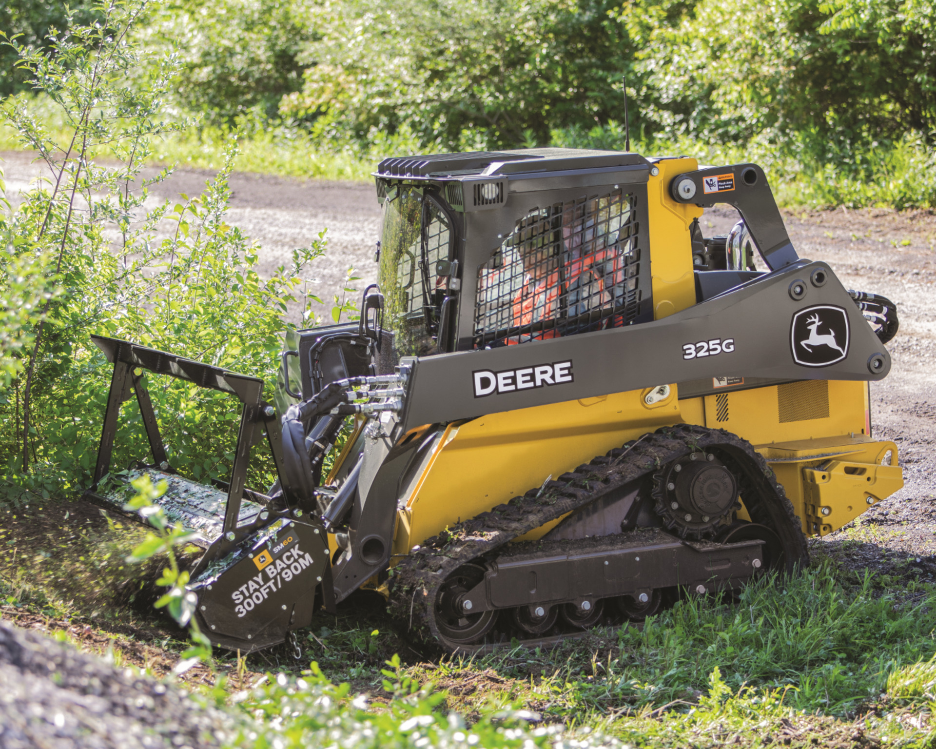 A 325G moves brush beside a road.