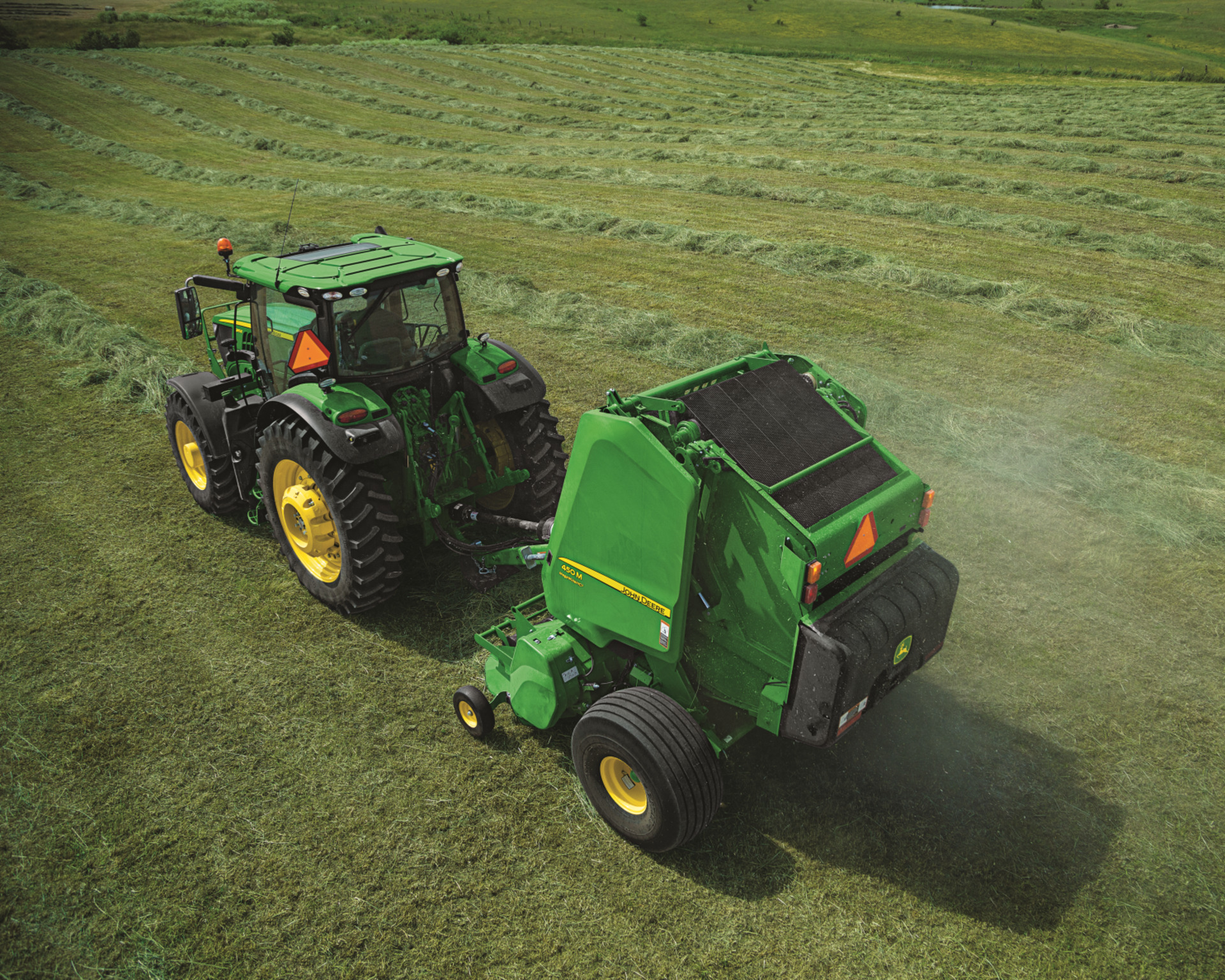 A 450M baler pulled by a John Deere tractor on a farm in Texas.