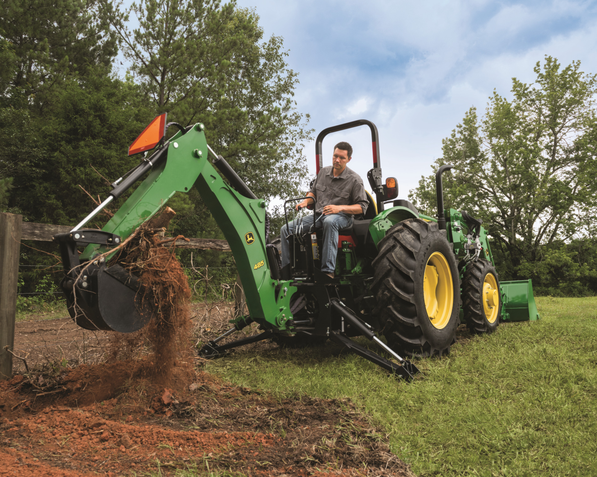 A property owner with a backhoe attachment on a John Deere 50565E tractor moves dirt in Texas.