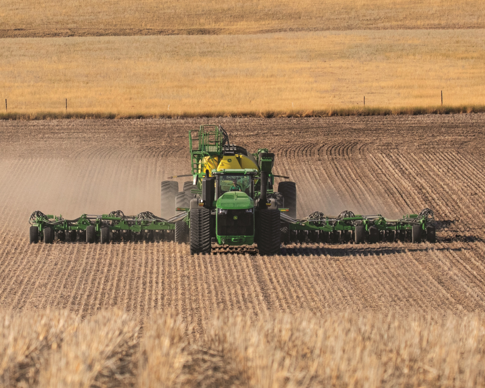 A John Deere 9RX tractor pulls an attachment in a field in Texas.