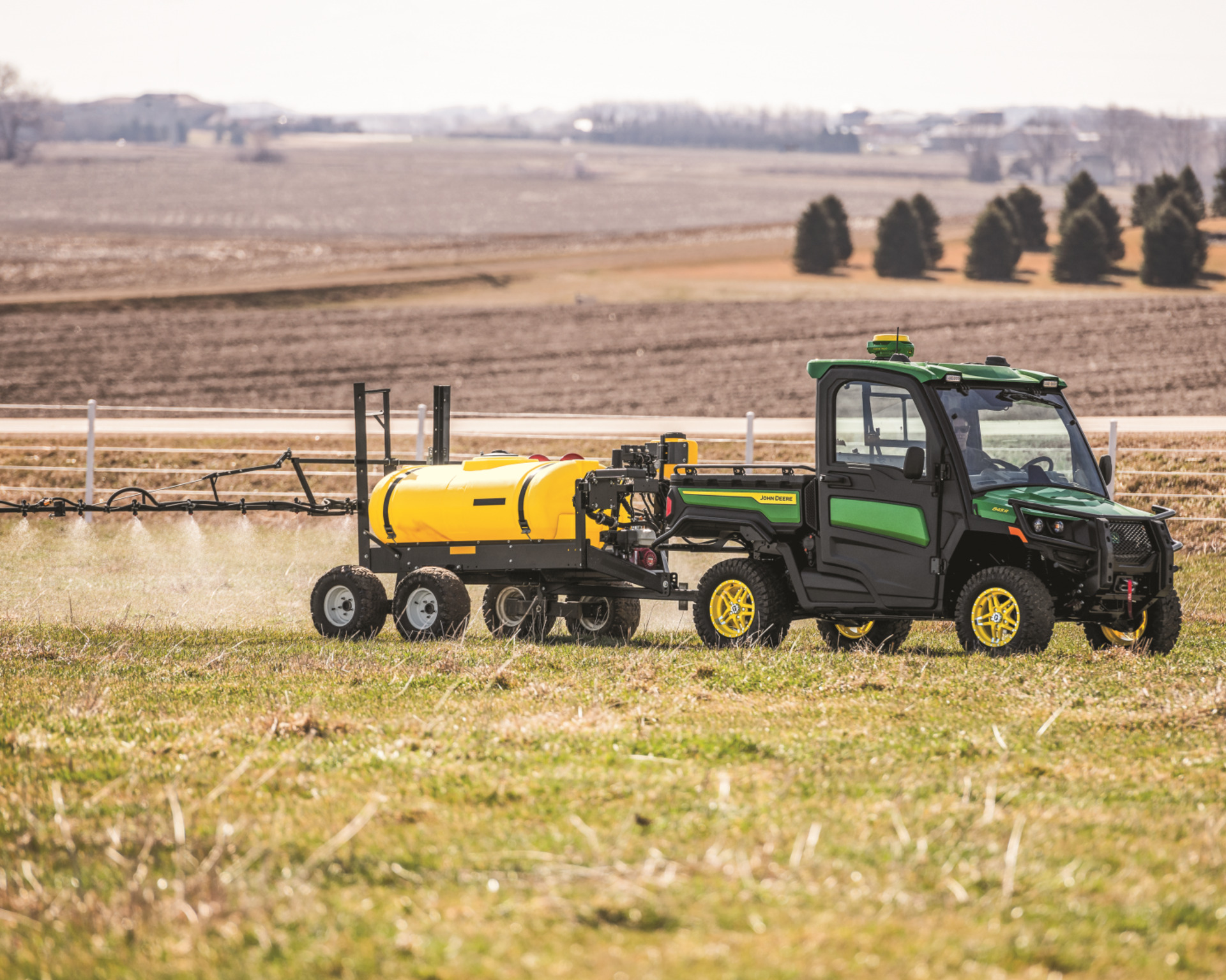 A Gator pulls a sprayer attachment on a farm in Texas.