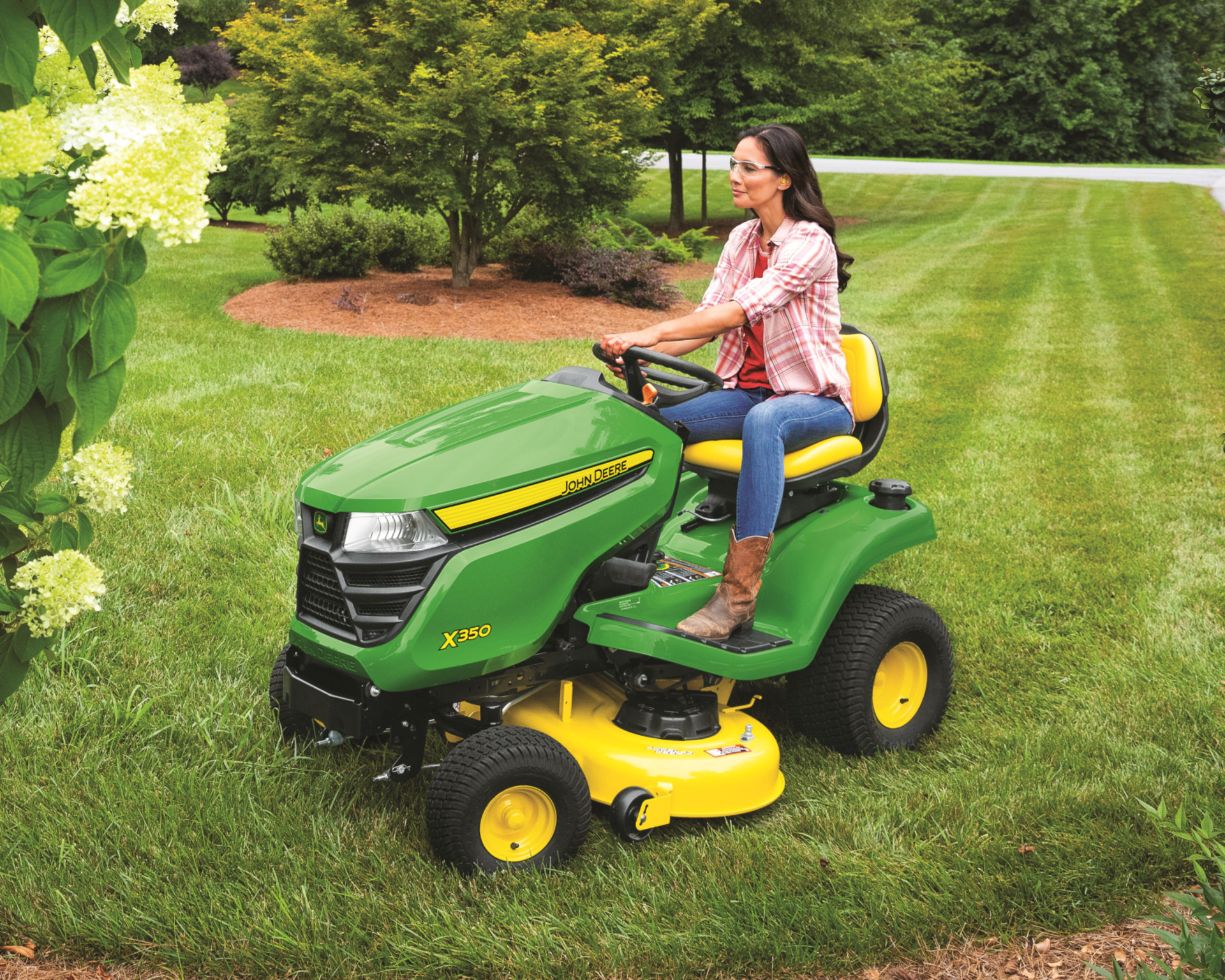 A homeowner mows their lawn with the John Deere X300 Select Series riding lawn mower.