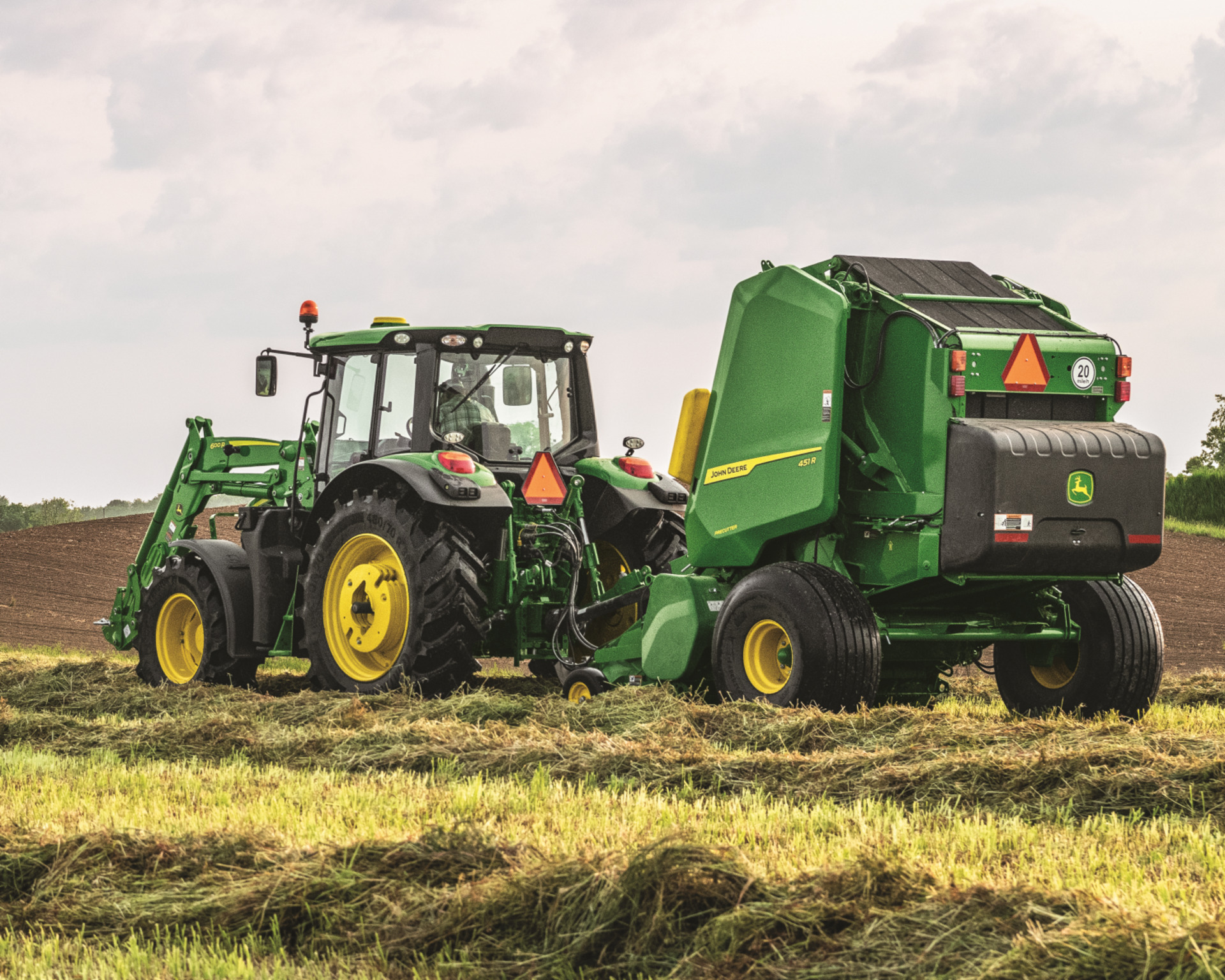A John Deere tractor pulls a round baler attachment in Texas.