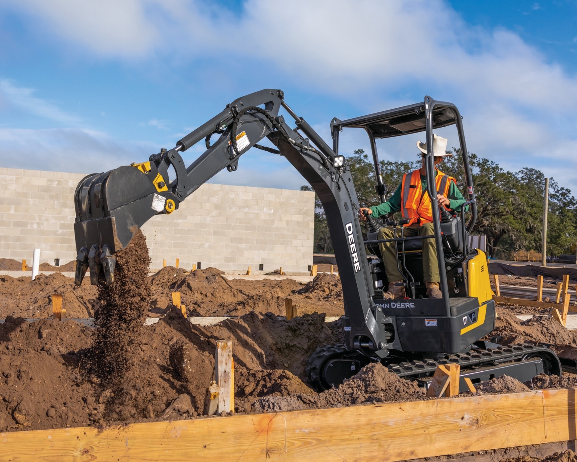 A compact excavator digs a hole on a construction site.
