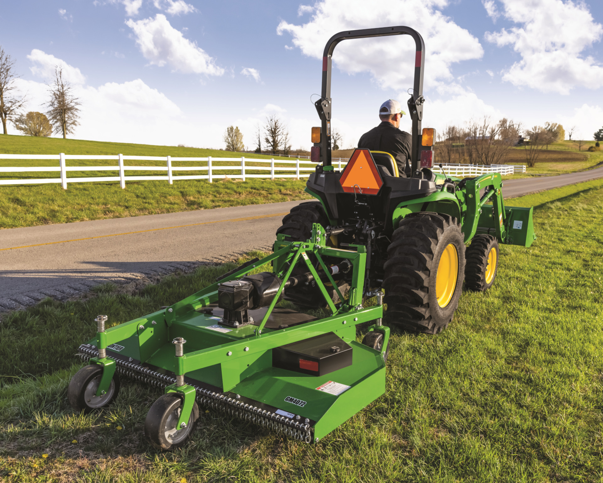 A rotary cutter on a John Deere tractor mows the side of the road to prevent road erosion in Texas.
