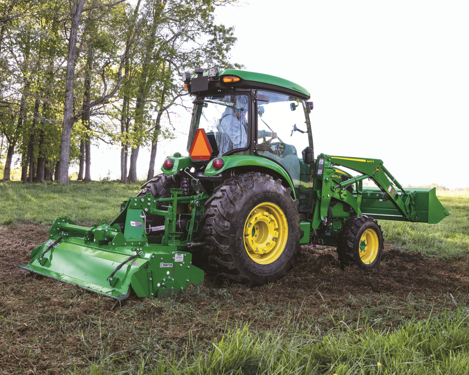 A John Deere tractor with a tiller attachment prepares the ground for a food plot.