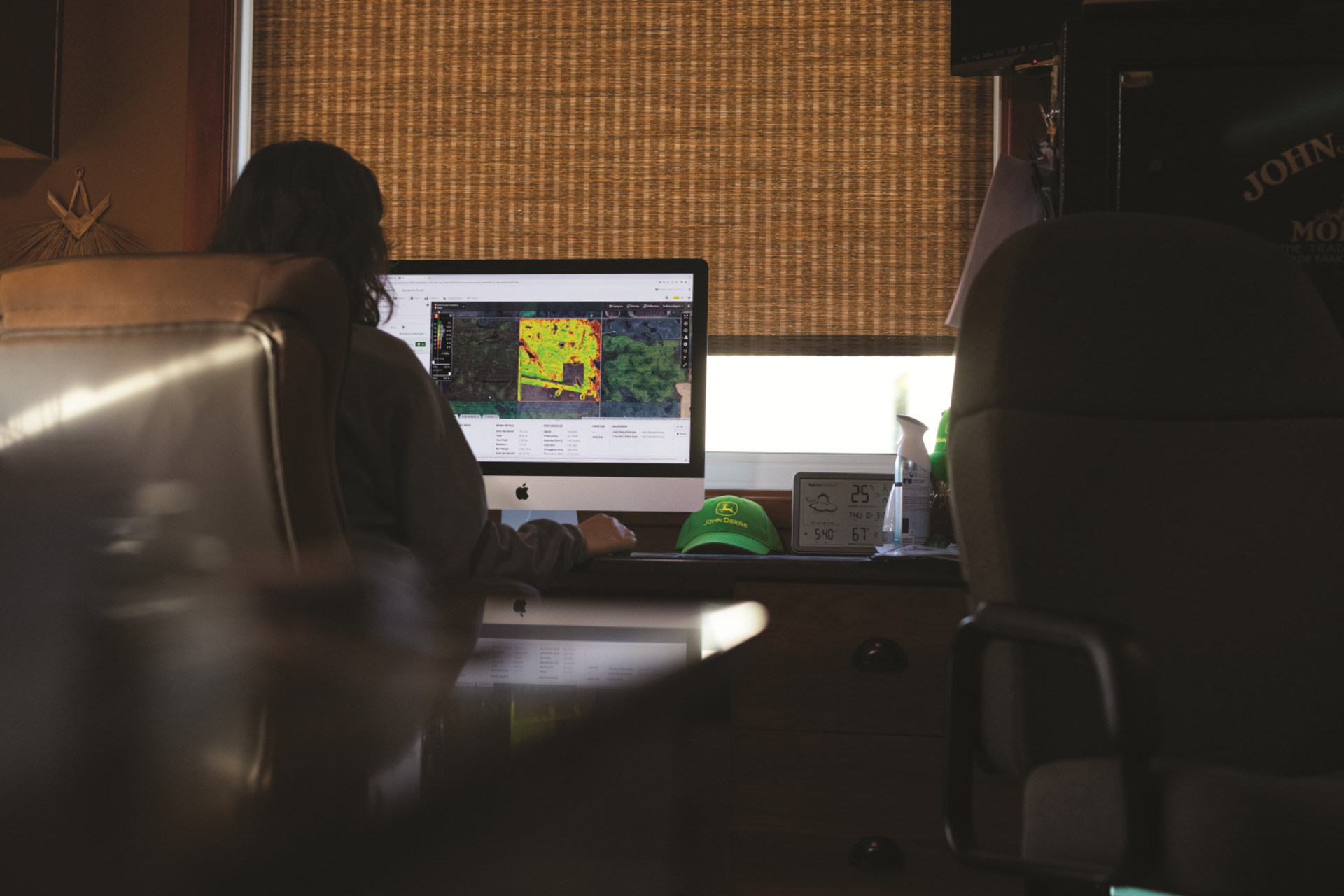A worker monitors a John Deere tractor remotely with remote diagnostic technology.