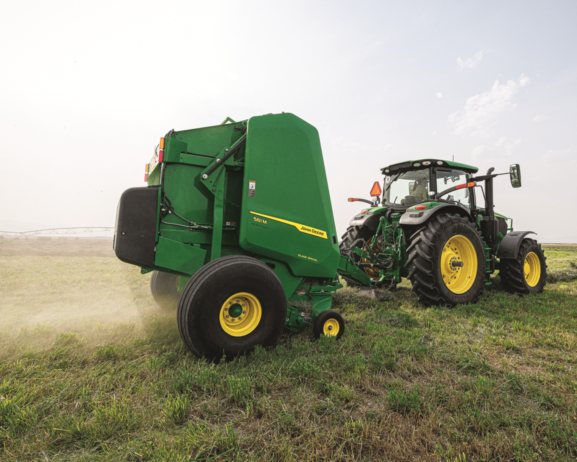 A John Deere 561M baler on a farm.