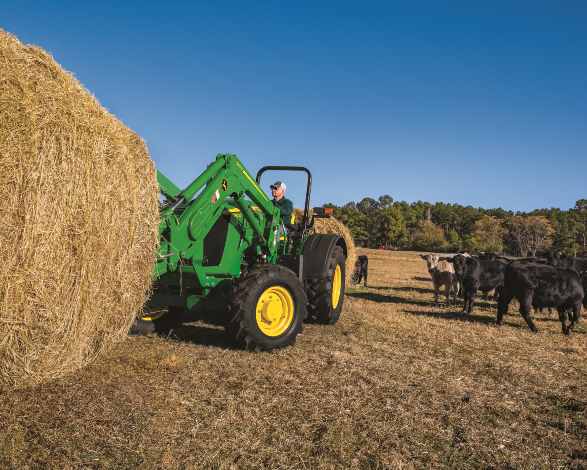 A 5 Series tractor lifts a hay bale for a cattle ranch in Texas.