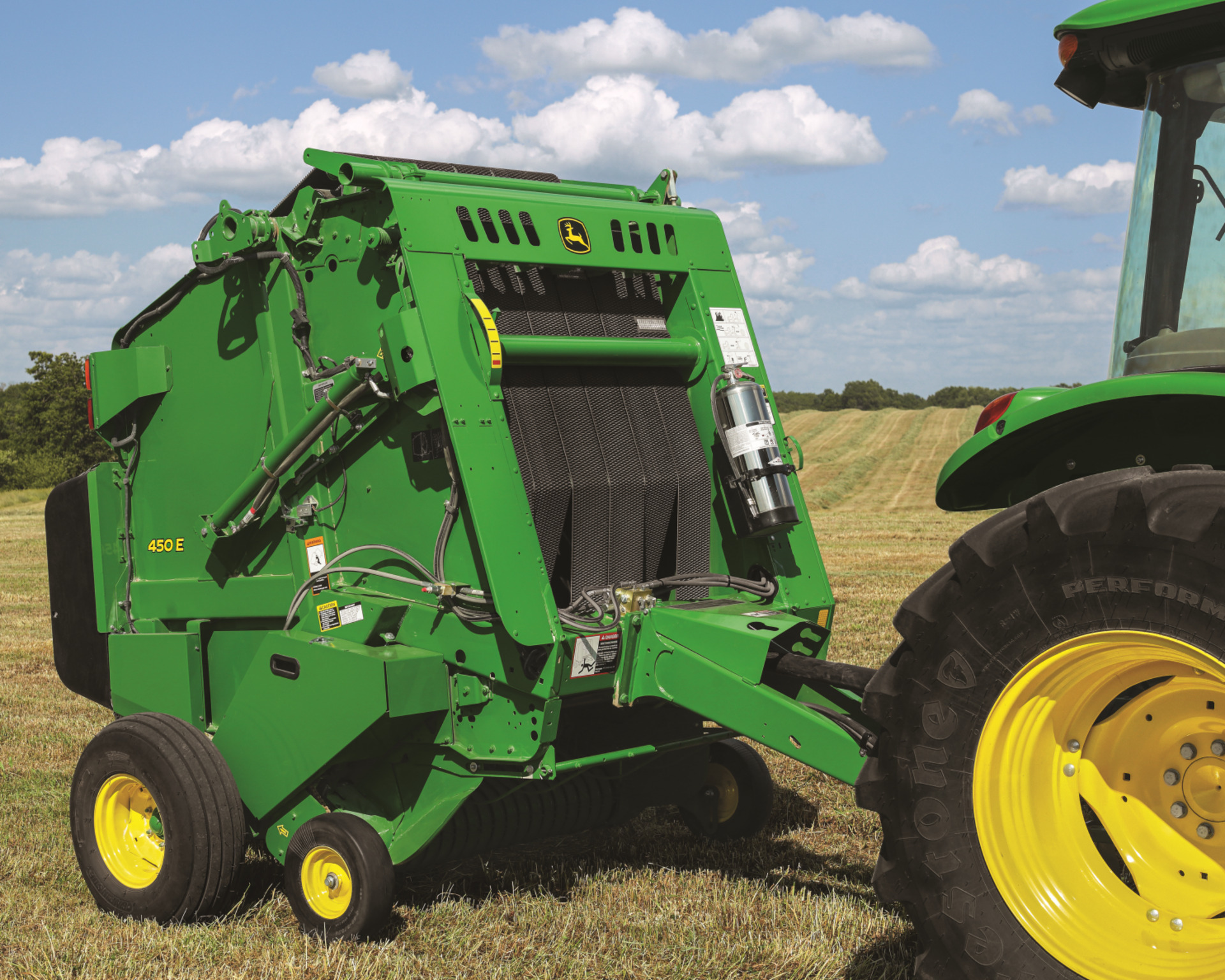 A John Deere 450E round baler pulled by a John Deere tractor in a field in Texas.