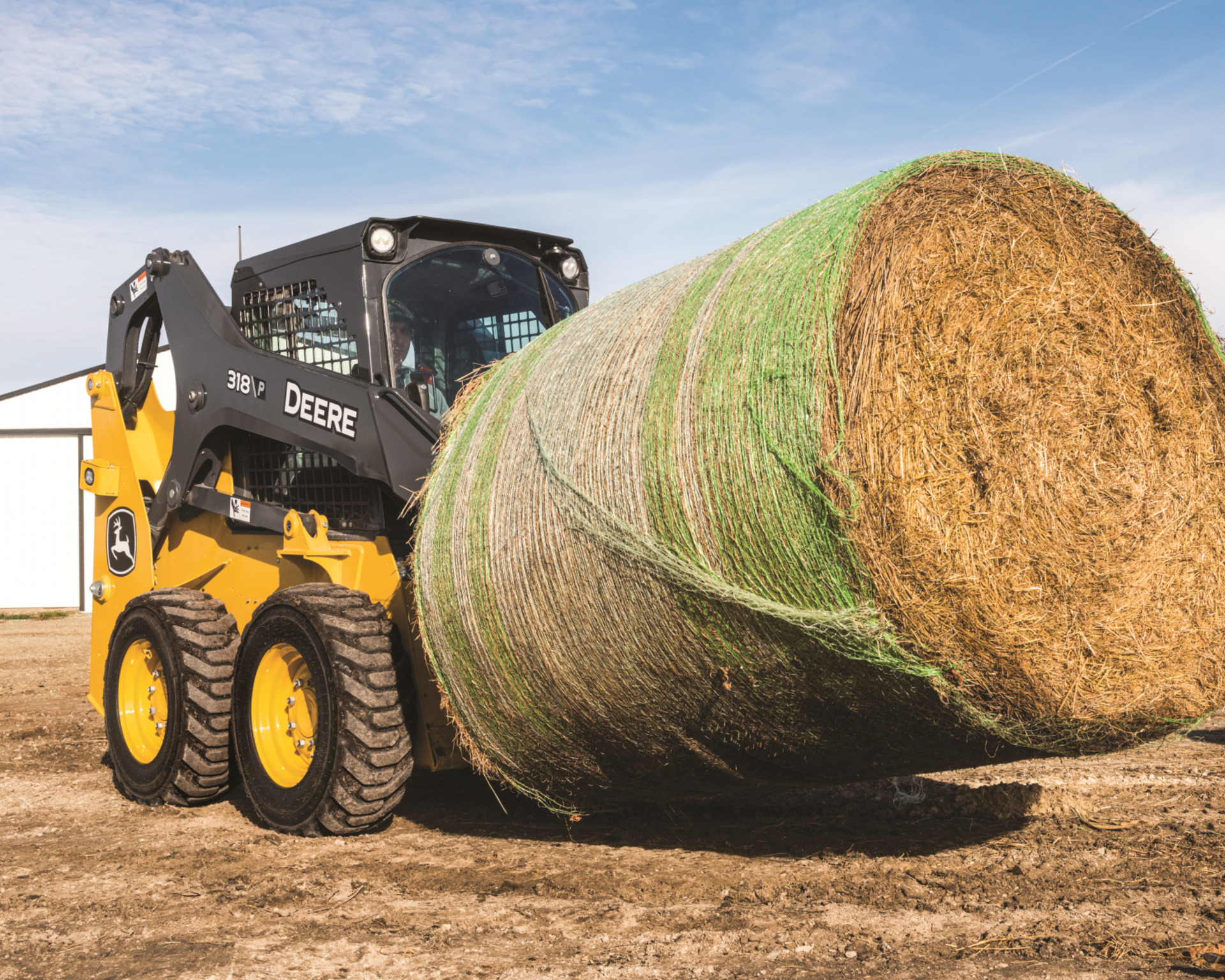 A skid steer lifts a hay bale in Texas.