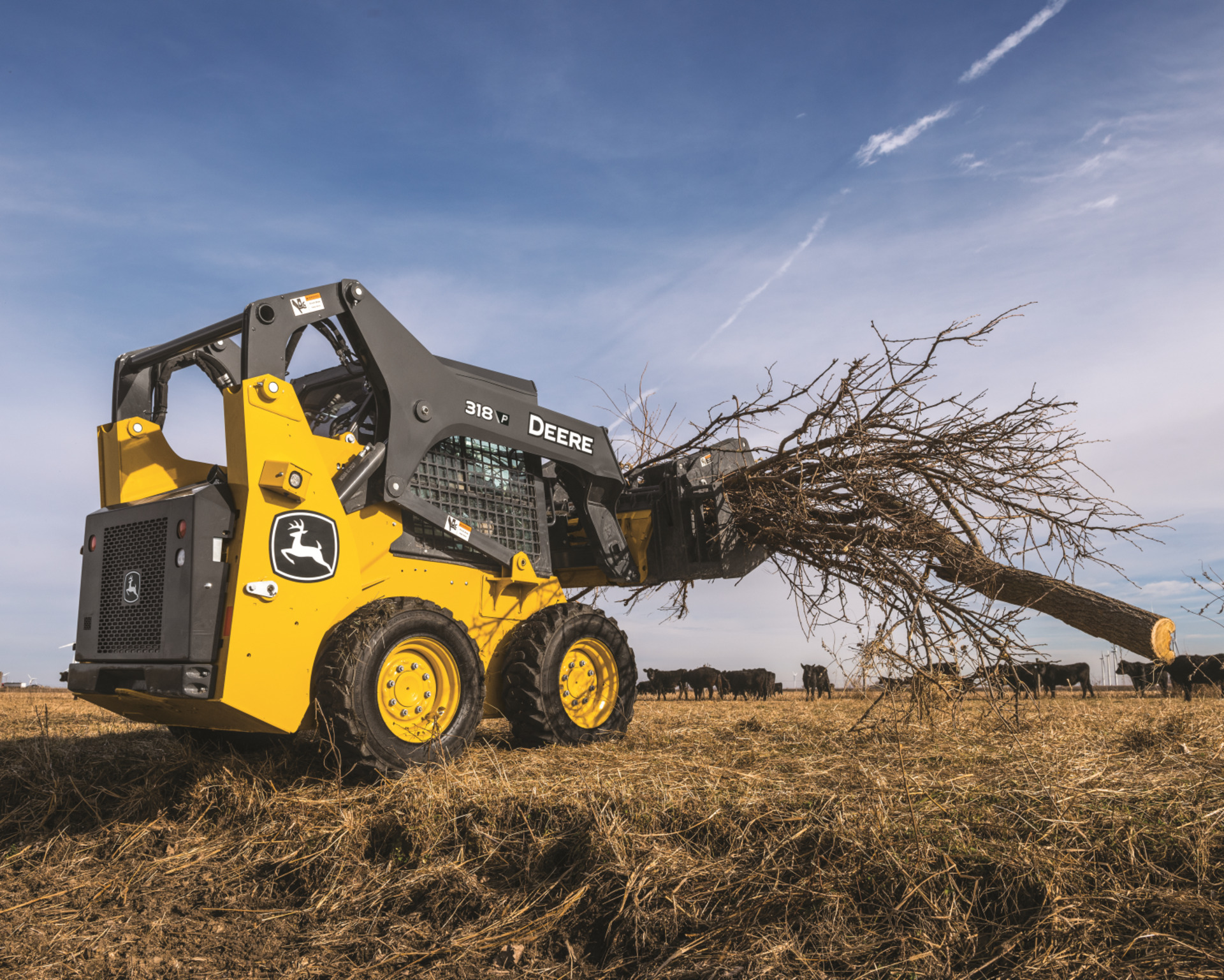 A skid steers lifts a tree branch on a ranch in Texas.