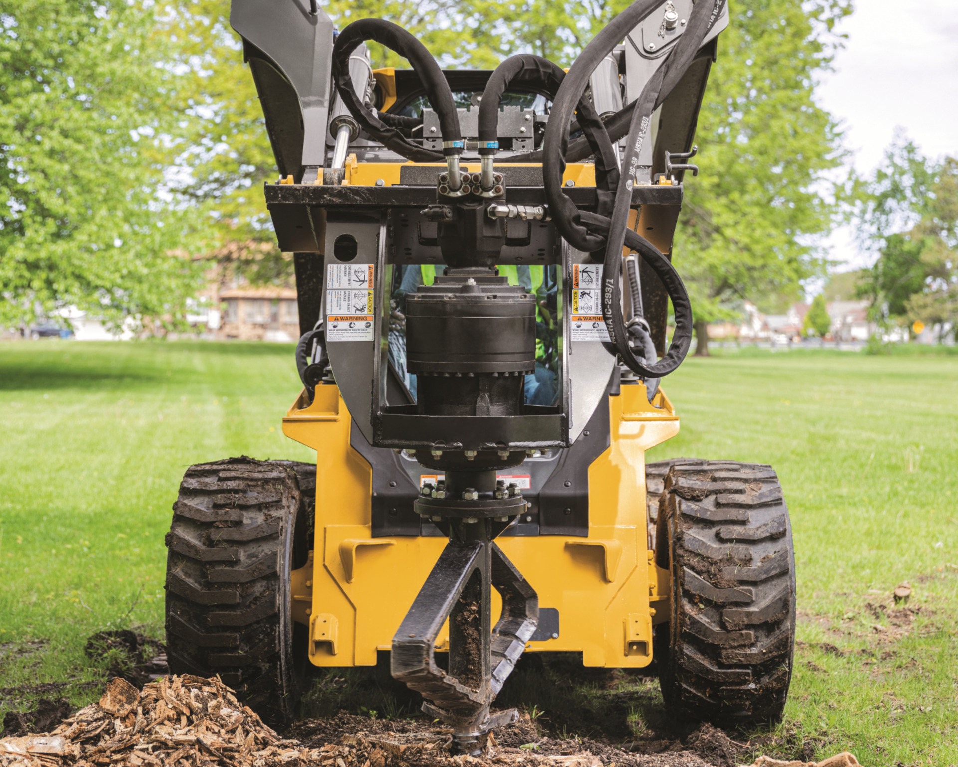 A skid steer with an attachment digs a hole.