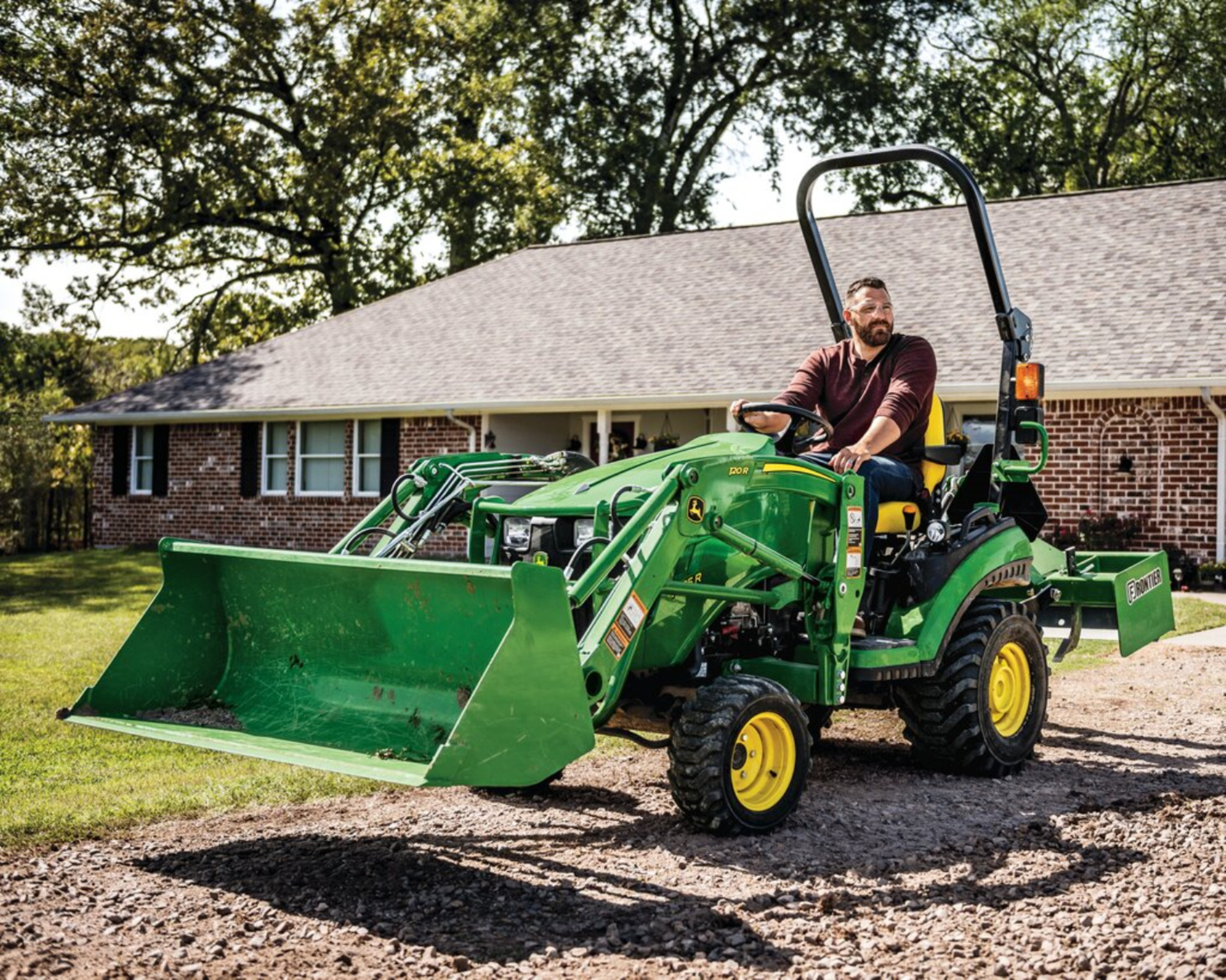 A property owner operates a John Deere tractor with a front-end loader and box blade in Texas.