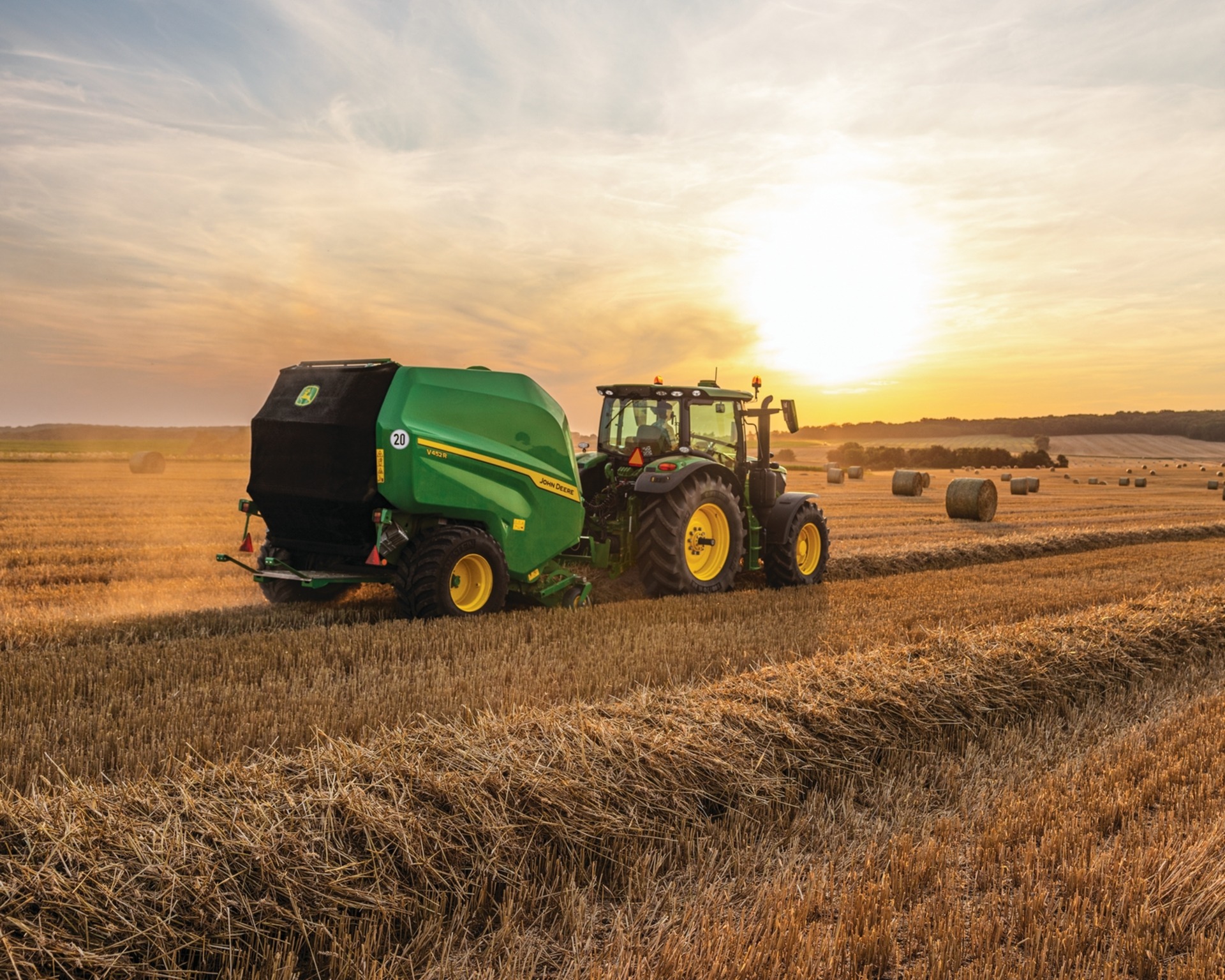 A John Deere tractor pulls a hay baler in a field in Texas.