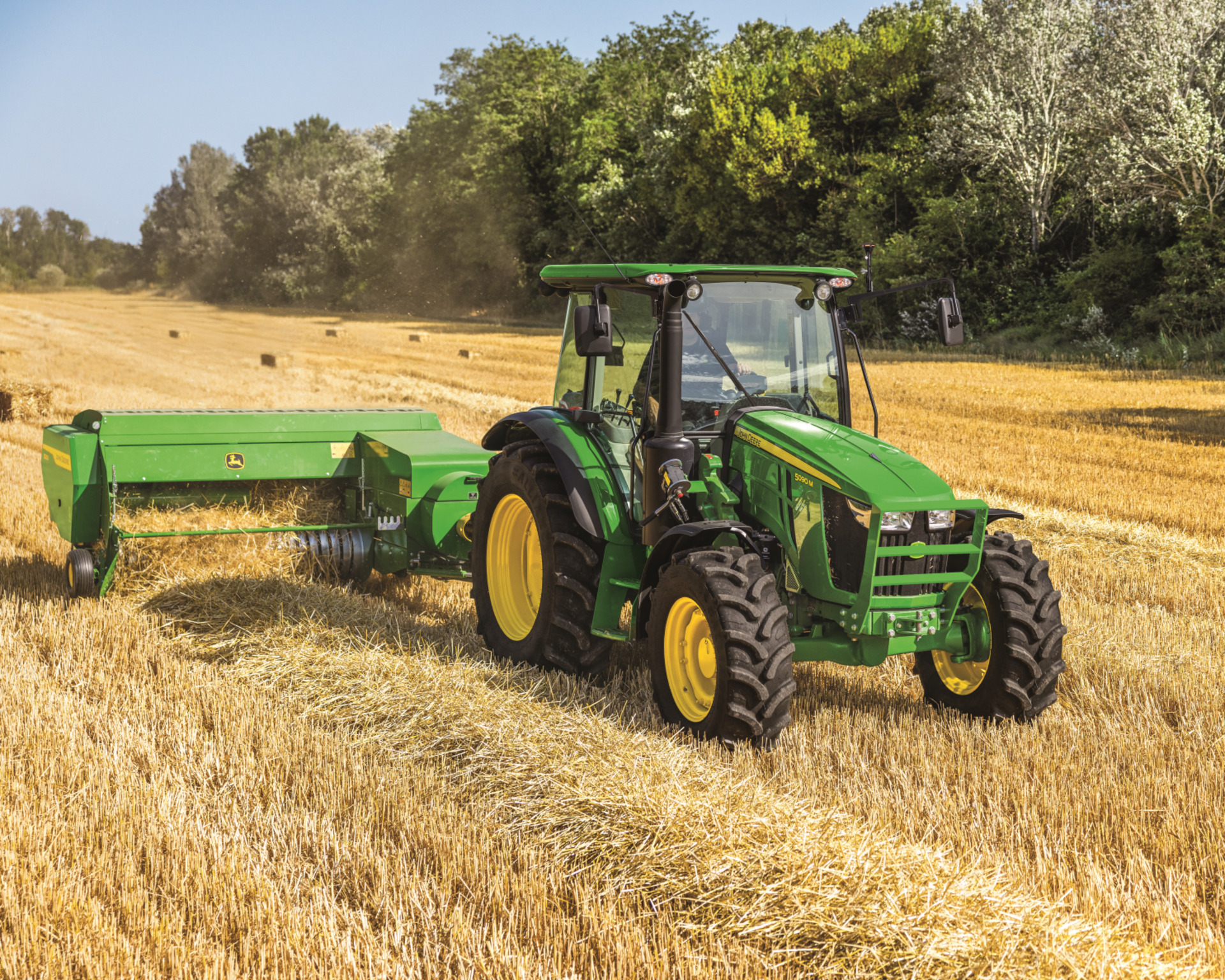 A John Deere tractor with a baling attachment bales hay in Texas.